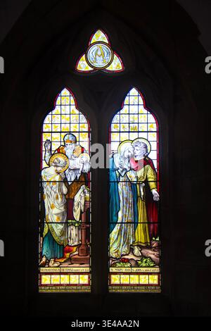 Vitrail orné représentant des scènes bibliques de la présentation dans le temple et Sainte Marie et Saint Jean à l'intérieur d'une église Banque D'Images