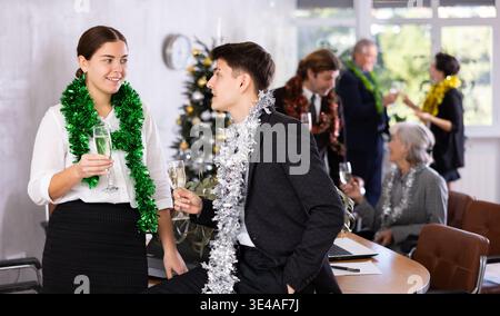 Joyeux collègues hommes et femmes avec des verres de champagne en fin de période de travail pendant la fête du nouvel an au bureau Banque D'Images