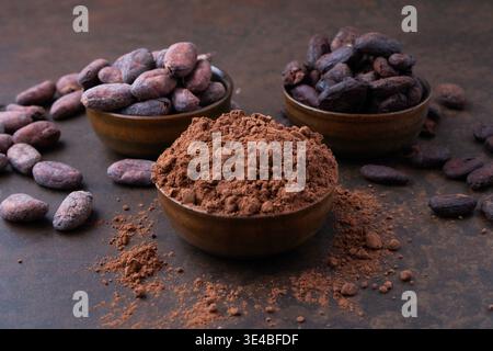 Fèves de cacao et un tas de poudre de cacao dans des bols en bois sur une table en pierre Banque D'Images