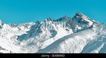 Un magnifique paysage grand angle avec des pics montagneux accidentés et enneigés et des crêtes alpines abruptes. La neige blanche brillante contraste fortement avec l'agai Banque D'Images
