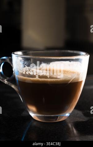 Café expresso foncé dans une tasse en verre clair sur un fond sombre Banque D'Images