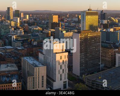 Un large prespectif aérien de Manchester baigné dans la lumière dorée du matin, mettant en évidence l'architecture diversifiée et les collines à l'horizon lointain. Banque D'Images
