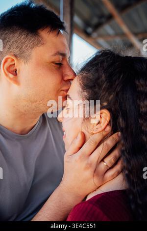 Moment tendre d'un jeune couple d'apparence slave partageant un doux baiser sur le front exprimant le soin de l'amour et la proximité émotionnelle dans la LIG naturelle Banque D'Images