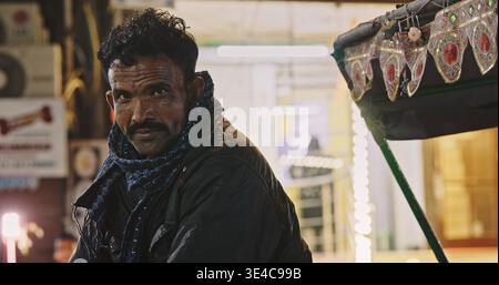 Cycliste rickshaw attendant les passagers au marché nocturne de Delhi Banque D'Images