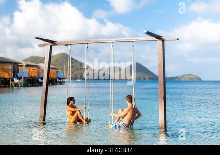 Un couple multiethnique diversifié, une femme asiatique et un homme caucasien, aiment se balancer doucement dans les eaux chaudes, entouré par de superbes paysages montagneux à Sainte-Lucie. Banque D'Images