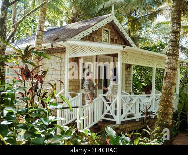 Couple profite d'un moment paisible ensemble sur un porche confortable d'un beau chalet dans le paradis tropical de Sainte-Lucie. Les plantes luxuriantes et la lumière du soleil créent une atmosphère de vacances idyllique. Banque D'Images