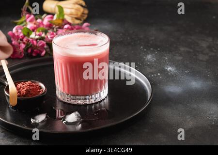 Latte matcha rose avec fleurs de sakura décorées en poudre sur fond sombre. Boisson tendance. Matcha rose glacé rafraîchissant. Gros plan. Banque D'Images