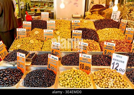 De nombreux bocaux d'olives sont exposés dans un étal du Grand Bazar. Les acheteurs examinent la variété et les prix des olives à Istanbul. Banque D'Images