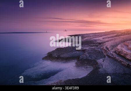 Côte de mer des Rocheuses et phare au coucher du soleil coloré en été Banque D'Images