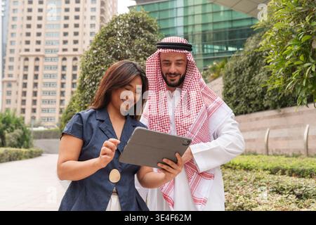 Les partenaires commerciaux asiatiques et arabes travaillent ensemble et discutent de l'investissement immobilier et de la finance sur une tablette. Banque D'Images