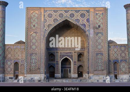 Entrée majestueuse de la madrasah Ulugbek - carreaux émaillés bleus, motifs, iwan arqué, minarets dans la lumière dorée, ciel bleu. Vue principale avant. Samarkand islam Banque D'Images
