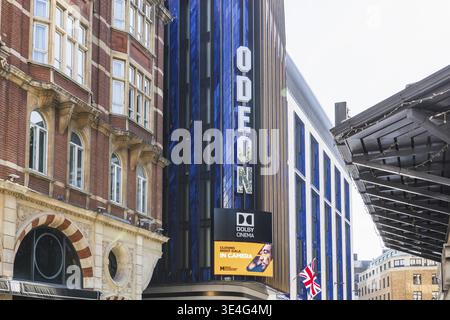 Vue au niveau de la rue de l'extérieur du cinéma Odéon mettant en vedette une signalisation blanche audacieuse sur une façade bleu foncé et un grand panneau d'affichage numérique contre une brique historique Banque D'Images