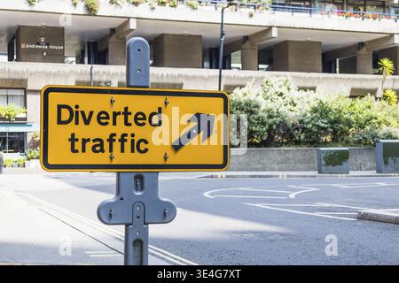 Panneau jaune de déviation avec flèche directionnelle placé sur le bord de la route urbaine Banque D'Images