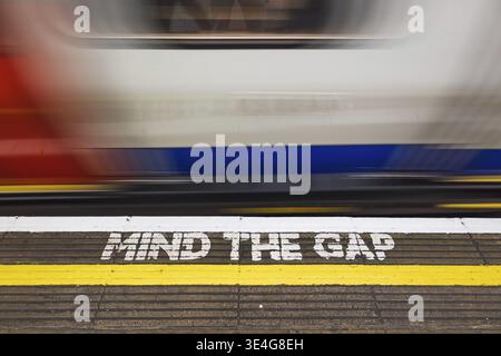 GARDEZ À L'ESPRIT LE message de sécurité GAP sur une plate-forme de métro londonienne alors qu'un train de métro à grande vitesse s'estompe, illustrant la prudence en matière de transport urbain et le trave ferroviaire britannique Banque D'Images