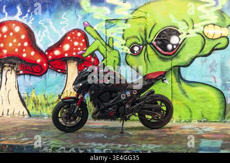 Moto sport noire garée dans le tunnel Graffiti de Leake Street à Londres, art de rue éclatant, couleurs néon et reflets imbibés de pluie. Londres, Royaume-Uni, 29 J. Banque D'Images
