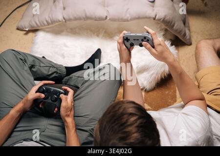 Gros plan de deux amis masculins jouant ensemble à la maison, jouant des jeux vidéo sur console pendant les loisirs, s'amusant et se relaxant tout en partageant Banque D'Images