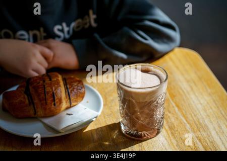 Chocolat chaud avec croissant et personne dans le café, petit déjeuner matinal confortable, scène de style de vie, atmosphère de café relaxant, confort et concept de loisirs Banque D'Images