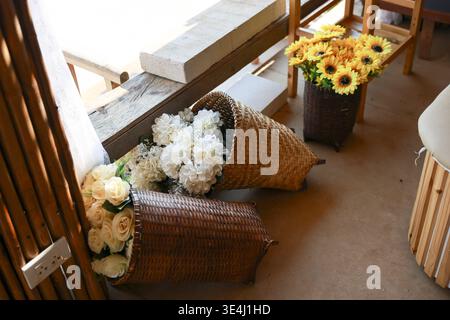 Décoration florale rustique avec panier de fleurs blanches renversées et bac à tournesol jaune reposant sur du parquet créant une atmosphère charmante et paisible Banque D'Images