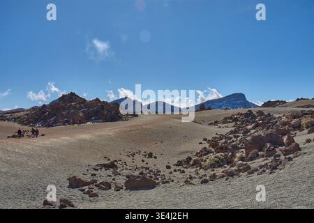 Teide, Tenerife, 13 janvier 2026, Un groupe de visiteurs se promène le long des sentiers de sable ocre et de roches basaltiques qui s’étendent au pied de l’imposant Mo Banque D'Images