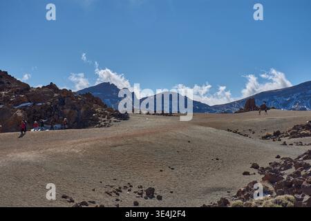Teide, Tenerife, 13 janvier 2026, Un groupe de visiteurs se promène le long des sentiers de sable ocre et de roches basaltiques qui s’étendent au pied de l’imposant Mo Banque D'Images