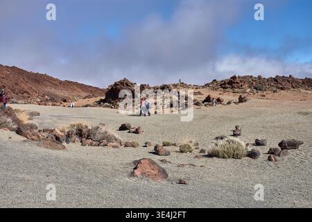 Teide, Tenerife, 13 janvier 2026, Un groupe de visiteurs se promène le long des sentiers de sable ocre et de roches basaltiques qui s’étendent au pied de l’imposant Mo Banque D'Images