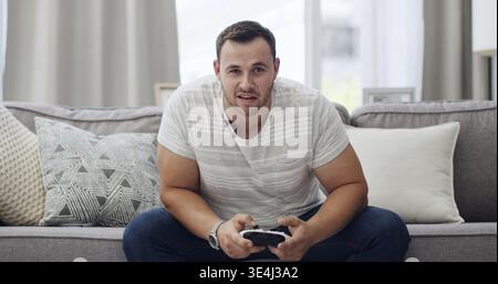 Homme, portrait ou joueur avec contrôleur sur canapé pour week-end, compétition ou match à la maison. Personne masculine, POV ou jouer avec la console sur le salon Banque D'Images