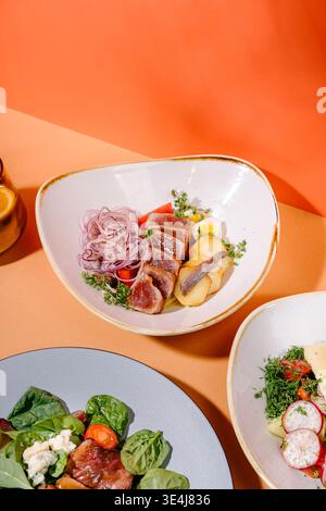 Vue de dessus du menu du restaurant trio. Salade nicoise avec thon poêlé, rôti de bœuf et salade de fromage bleu, salade de légumes frais avec fromage brynza. Banque D'Images