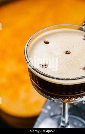 Gros plan d'un espresso martini dans un verre coupé, fait avec de la vodka, de la liqueur de café Kahlua, de l'espresso frais et du sirop de sucre, recouvert de mousse crémeuse et Banque D'Images