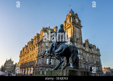 Le Grand Balmoral Hotel avec son emblématique tour de l'horloge surplombe une statue équestre historique sur une rue animée d'Édimbourg, baignée par la lumière chaude de l'heure d'or A. Banque D'Images