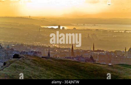 Le coucher de soleil doré baigne les gratte-ciel d'Édimbourg et le Firth of Forth vu depuis Arthur's Seat, avec des collines superposées, des ponts lointains et une atmosphère brumeuse Banque D'Images