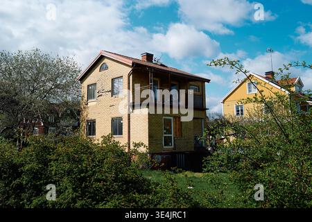Villa fonctionnelle avec briques cassées. La végétation du jardin cache les niveaux inférieurs et la zone du porche. Nynashamn, comté de Stockholm, Suède, 11 mai 2025 Banque D'Images