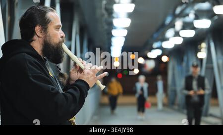 Moscou, Russie - 25 août 2025 : musicien de rue jouant à la flûte à bec dans le passage souterrain urbain la nuit, créant de la musique Banque D'Images