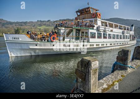 Le soleil brille sur le lac Windermere tandis que le charmant bateau à vapeur Swan vous attend à l'embarcadère du lac. Les passagers profitent d'une journée délicieuse sur cette photo Banque D'Images