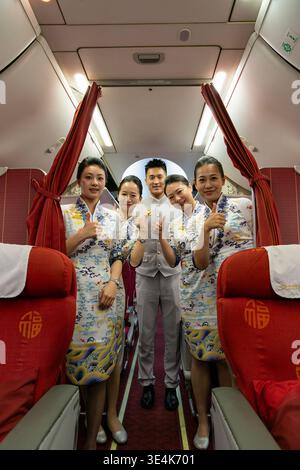 Singapour - 7 décembre 2025 : portrait de groupe complet de l'équipage de cabine de Hainan Airlines, des agents de bord et un steward masculin, debout et posant Banque D'Images