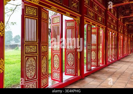 Portes traditionnelles en bois rouge et or à l'intérieur de la Cité pourpre interdite dans la ville impériale de Hué, Vietnam. Architecture royale historique des Nguyen Banque D'Images