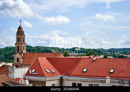 Une vue panoramique sur un paysage urbain européen avec des toits traditionnels en tuiles rouges au premier plan. Un clocher d'église historique avec une flèche en cuivre Banque D'Images
