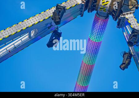Attraction animée avec lumières LED multicolores et structure métallique sur un ciel bleu vif par une journée ensoleillée. Banque D'Images
