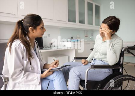 Médecin consultant une patiente en détresse en fauteuil roulant Banque D'Images
