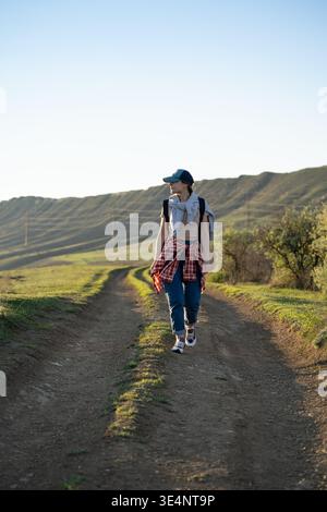 Femme confiante voyageur solo marche sur la route de trek dans les montagnes avec sac à dos apprécie le paysage de la nature. Banque D'Images