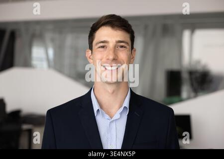 Portrait de tête de jeune homme d'affaires debout avec confiance dans le bureau contemporain Banque D'Images