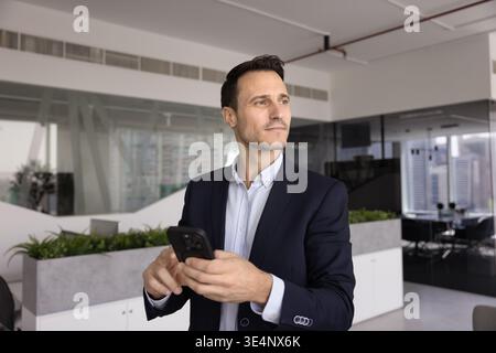 Adulte hispanique masculin professionnel de planification d'entreprise appel de téléphone portable dans le bureau Banque D'Images