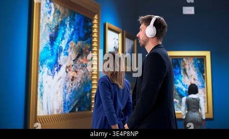 Jeunes visiteurs plongés dans la visite du musée avec écouteurs, explorant les expositions d'art et d'histoire Banque D'Images