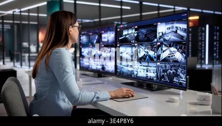 Agent de sécurité féminin surveillant plusieurs écrans de surveillance dans Control Center Banque D'Images