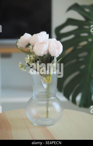 Fleurs placées dans un vase transparent sur une table en bois Banque D'Images