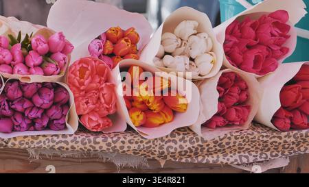 Bouquets colorés de tulipes enveloppés dans du papier couché sur une stalle Banque D'Images