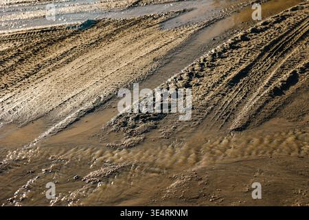 Route boueuse avec écoulement d'eau et traces profondes de pneus, gros plan. Concept : dommages à la route après l'hiver Banque D'Images