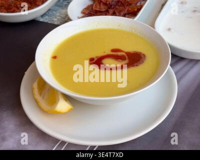 Soupe crémeuse aux lentilles servie avec tourbillon de beurre de paprika et citron sur une assiette blanche. Cuisine turque traditionnelle, présentation d'entrée de restaurant et Banque D'Images