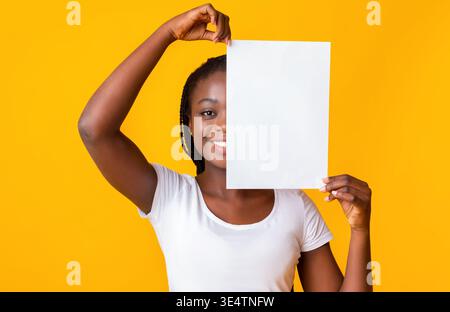 Femme noire couvrant la moitié de son visage avec du papier propre Banque D'Images