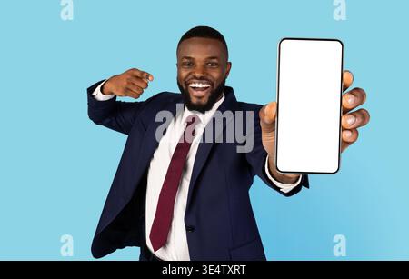 Beau homme d'affaires noir en costume pointant vers le smartphone Big Blank en main Banque D'Images