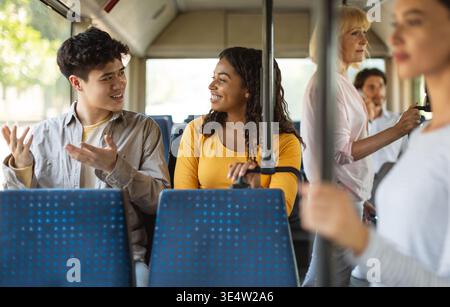 Heureux jeunes amis multiraciaux prenant le bus ensemble Banque D'Images